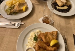 Eine gedeckter Tisch mit verschiedenen Fischgerichten und halbgeleerten Gläsern