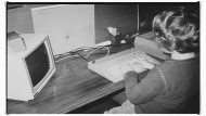 Schwarz-weiß Foto: Ein Kind sitzt vor einem Atari-Computer an einem Schreibtisch.