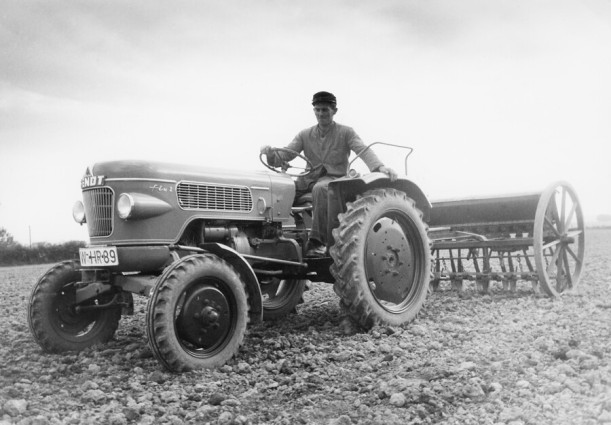 Ein Mann sitzt auf einem alten Fendt-Traktor, der auf einem Feld steht. Das Bild ist scharz-weiß.