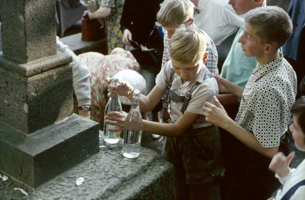 Kinder mit Flaschen an einem Brunnen