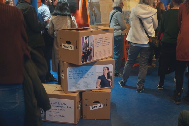 Kartons mit Schrift und Fotos sind Teil einer Ausstellung, die von vielen Menschen besucht wird.