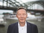 Porträt eines Mannes mit geschlossenen Augen am Rhein, im Hintergrund ein Schiff