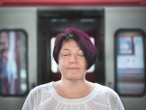 Porträt einer  Frau mit geschlossenen Augen vor einem Zug