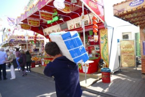 Ein Mann geht über den Jahrmarkt und trägt ein Paket mit Papierhandtüchern über der Schulter