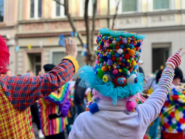 Zwei bunt verkleidete Menschen jubeln einen Karnevalswagen zu