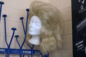 An einem Garderobenhaken hängt eine Schulterlange, blonde Perücke.