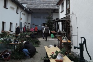 Ein Innenhof in Schweinheim, in dem zahlreiche Dorfbewohner*innen gemeinsam Adventskränze basteln.