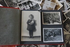 Aufgeschlagenes Fotoalbum mit schwarz-weiß-Abbildungen von Kindern auf einem Hintergrund von weiteren schwarz-weiß-Fotografien