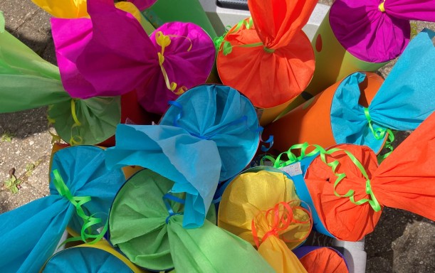 In einer Plastikbox stehen aus buntem Paper gebastelte Schultüten.
