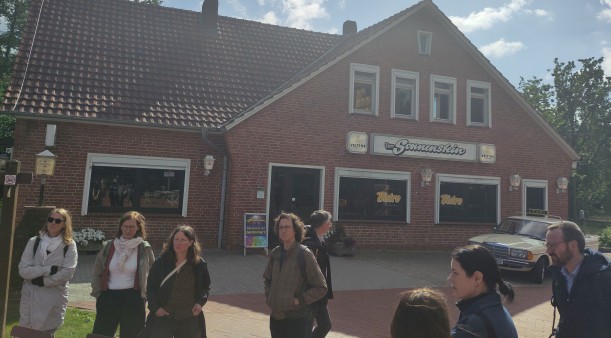 Vor einem Haus mit der Aufschrift "Zum Sonnenstein" steht eine Personengruppe