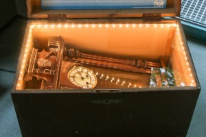 Geöffneter, beleuchteter Ausstellungskarton, der eine Uhr enthält.