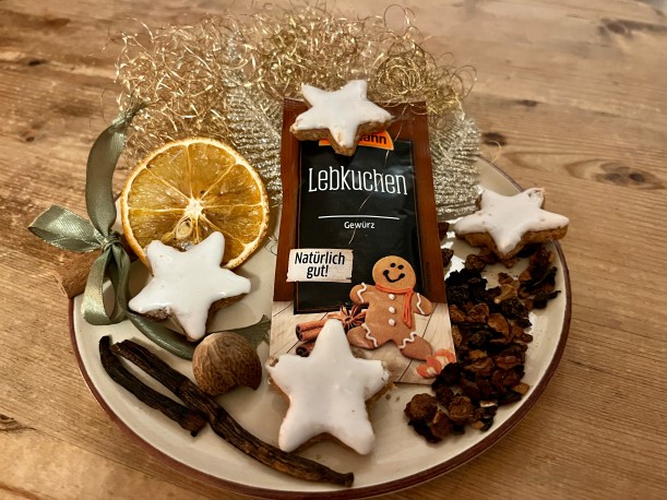 Auf einen Teller sind unterschiedliche Gewürze, Weihnachtsdekoration und eine Tüte mit der Aufschrift „Lebkuchengewürz“ angeordnet. Foto: Gabriele Dafft/LVR-ILR