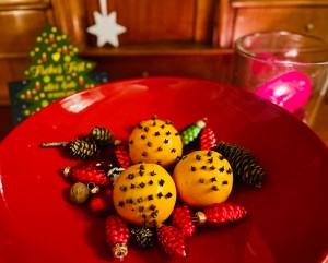 Schale mit weihnachtlicher Dekoration, darunter drei Orangen, die mit Gewürznelken gespickt sind.