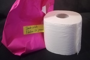 Foto: ausgepacktes rosafarbenes Geschenkpapier, daneben eine Rolle Toilettenpapier