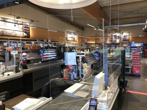 Eine von der Decke gehängte Scheibe aus Plexiglas dient als Schutzvorrichtung der Mitarbeitenden an der Supermarktkasse.