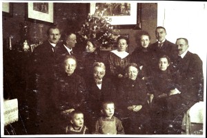 Viele Menschen in Festkleidung haben sich vor einem Weihnachtsbaum versammelt.