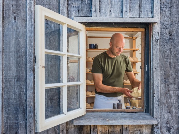 Ein Mann mit Schütze ist durch ein Fenster dabei zu sehen, wie er Teiglinge abwiegt.