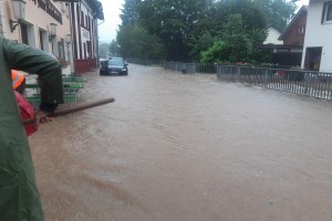 Hochwasser in Euskirchen Schweinheim. Eine Person versucht mit einer Schaufel, Sand als Schutz zu verteilen.