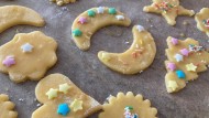 Ausgestochene und mit buntem Zuckerdekor versehen Plätzchen auf einem Backblech.