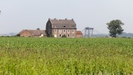 Verlassenes Haus bei Düren-Merken an der Abbruchkante vom Tagebau Inden, Schaufelbagger im Hintergrund.