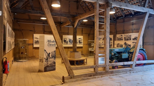 Blick in die Ausstellung: Neben vielen Schwarz-Weiß-Aufnahmen befindet sich ein Traktor in der Scheune.