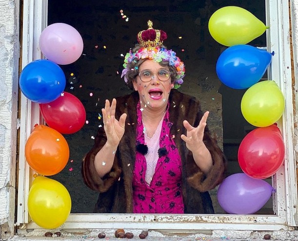 Maria Kleingebaeck, eine schrullige, ältere Dame und Protagonistin des Videos, liegt im Fenster, das mit Luftballons geschmückt ist, und wartet auf den KArnevalsumzug.