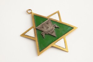 Goldfarbener sechzackiger Davidstern, darin grün unterlegtes Dreieck, darauf auf weiterem Dreieck drei Buchstaben „K“ und der Text „Kleiner Kölner Klub 1929“